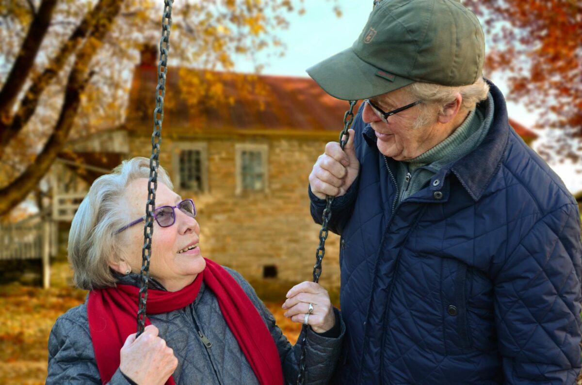 Photo by Pixabay A happy elderly couple sharing a joyful moment on a swing in autumn setting.